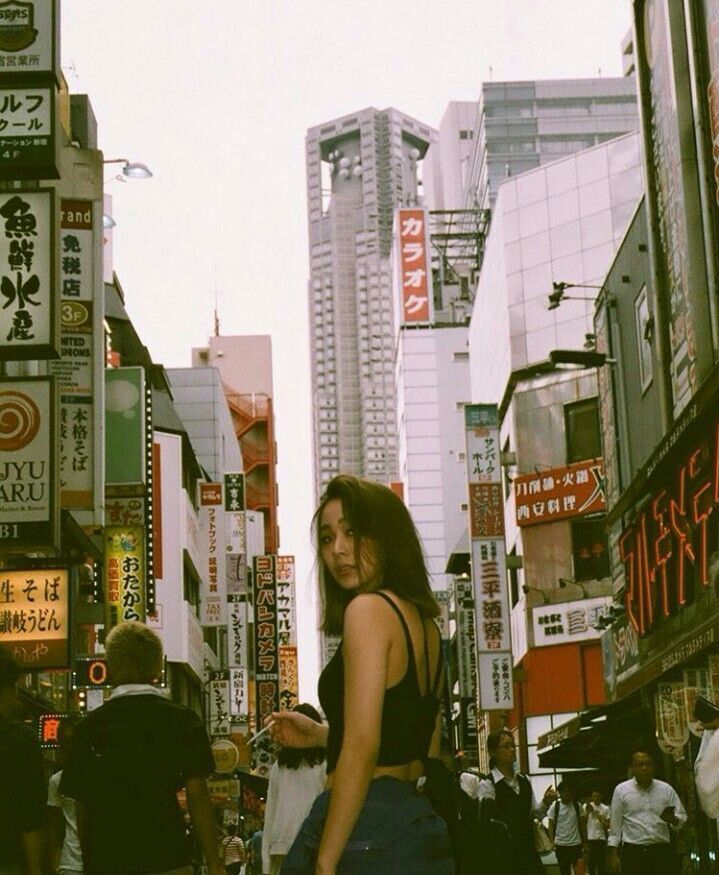 a woman standing in the middle of a busy city street