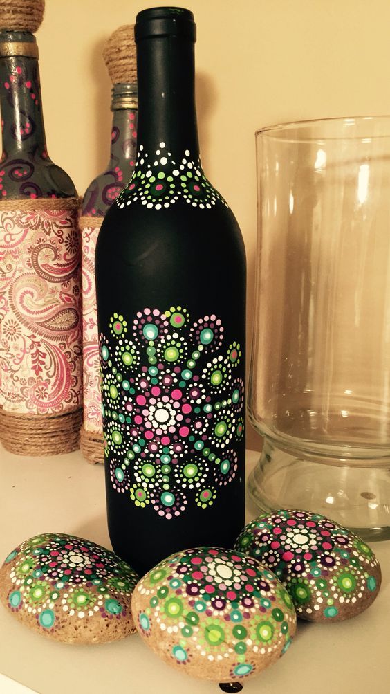 there are three decorated bottles and some cookies on the counter next to each other,