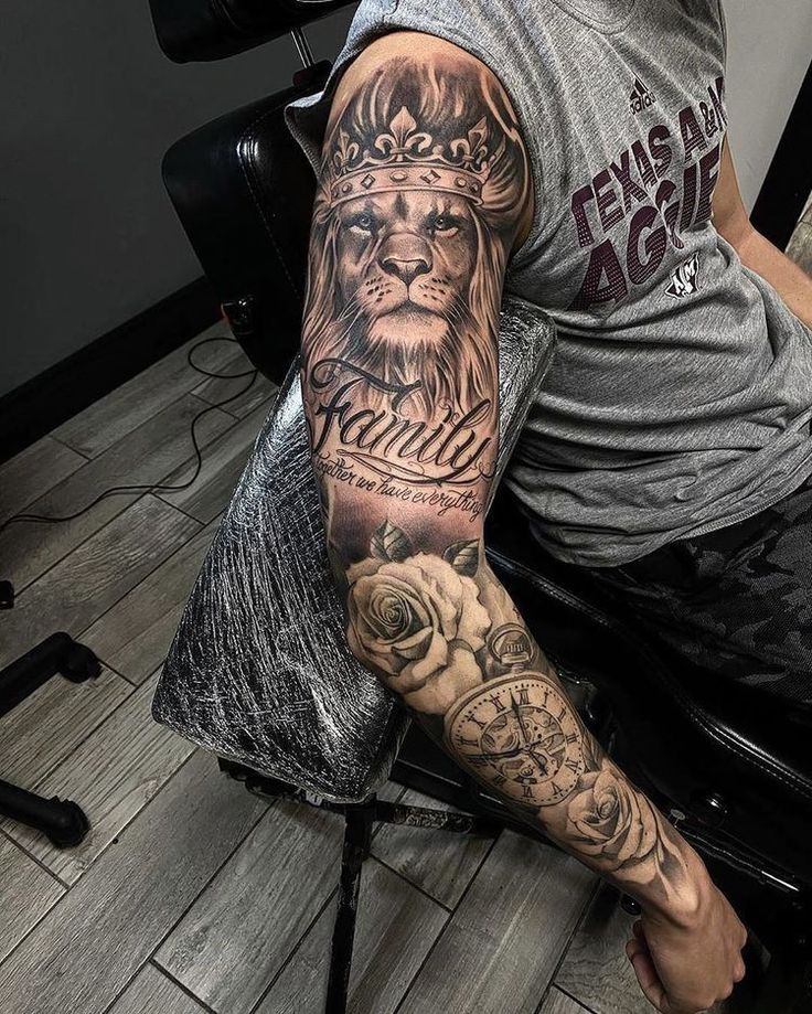 a man with a lion tattoo on his arm sitting in front of a computer desk