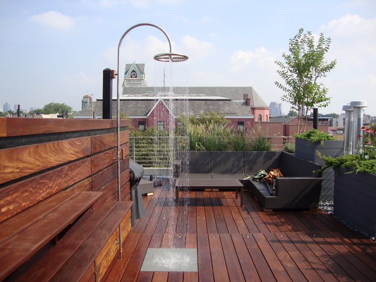 an outdoor shower on the roof of a building with lots of plants and potted plants