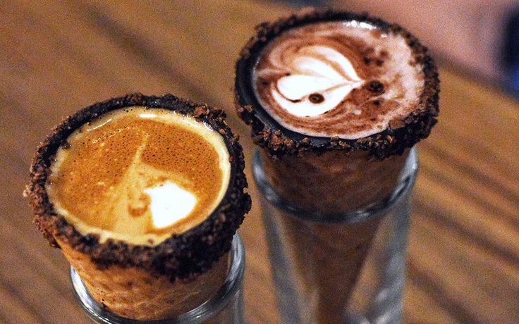 two glasses filled with different types of drinks on top of a wooden table next to each other