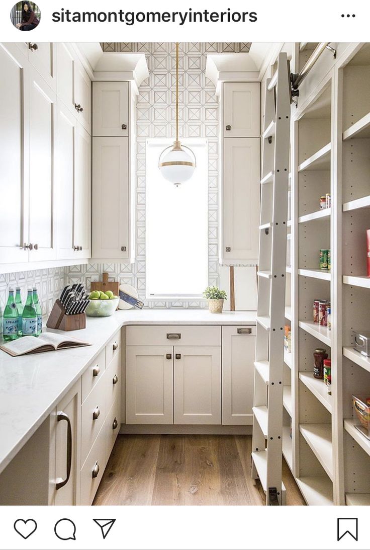 a kitchen with white cupboards and shelves filled with food, drinks and other items