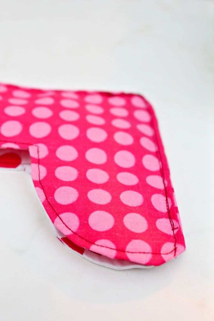 a pink and white polka dot covered case on a table with a cell phone in it