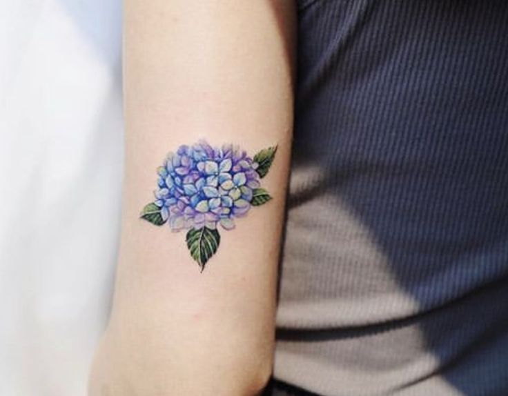 a woman's arm with a blue and purple flower tattoo on her left arm