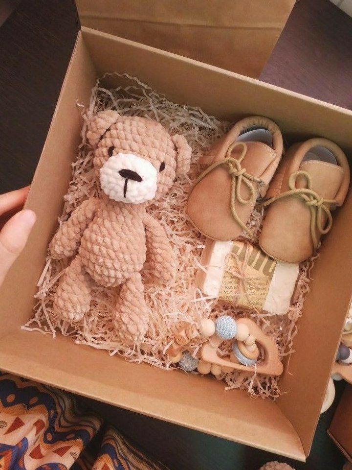 a teddy bear sitting inside of a box filled with baby shoes and other items in it