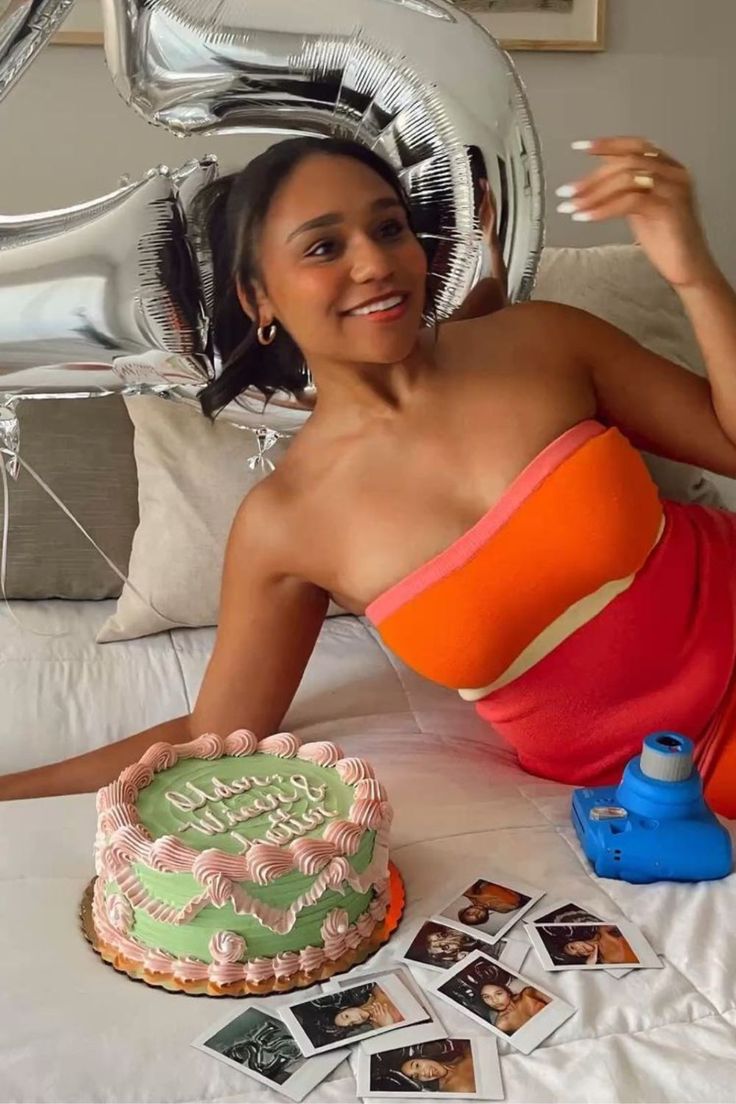 a woman sitting on a bed in front of a cake and balloon shaped number six