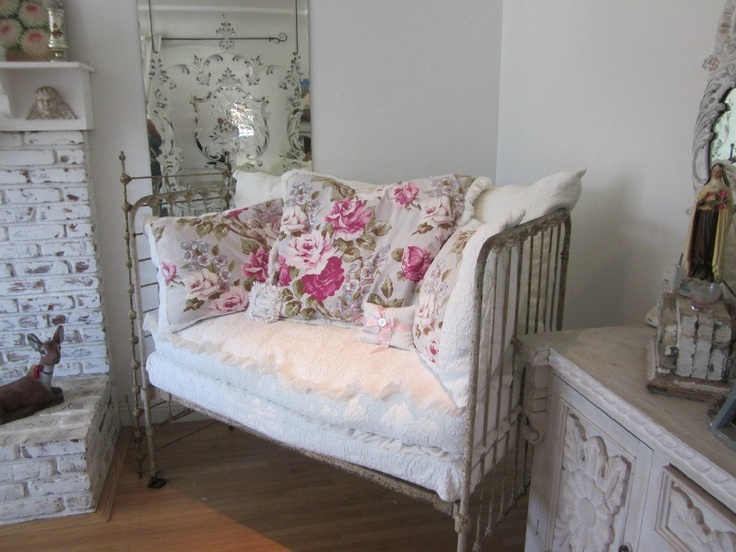 a white couch sitting next to a mirror on top of a wooden floor in a room