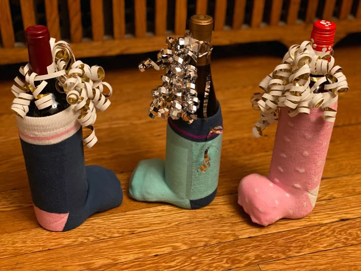 three wine bottles are decorated with bows and ribbons as they sit on the floor next to each other