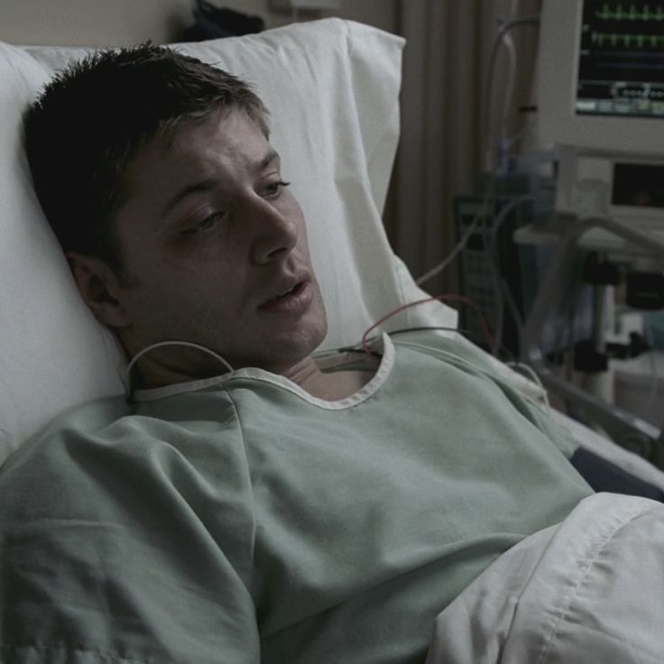 a man laying in a hospital bed with headphones on