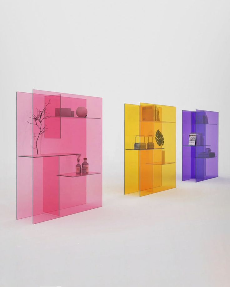 three different colored glass shelves with vases on each one and a plant in the middle