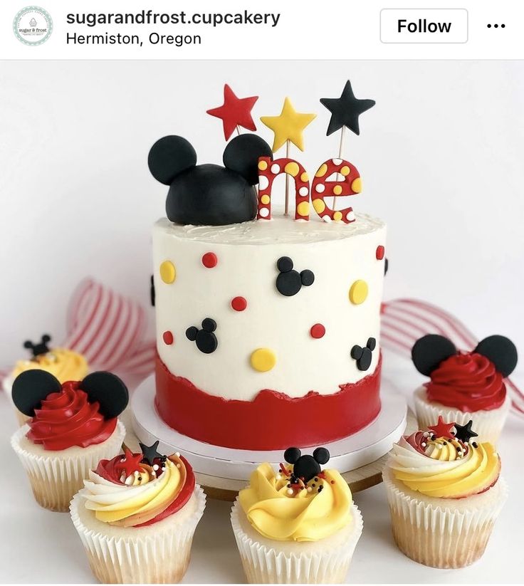 a mickey mouse birthday cake surrounded by cupcakes