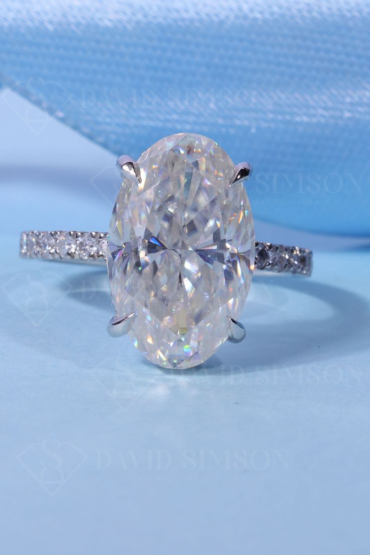 an oval cut diamond ring on a blue background