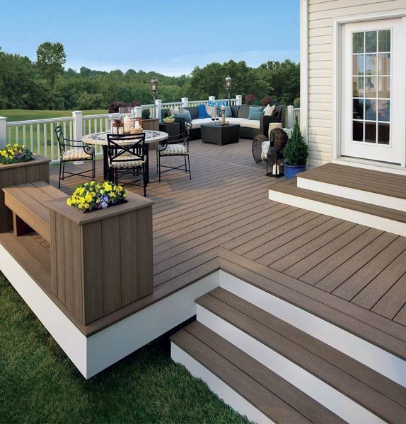 a deck with chairs, table and flowers on it