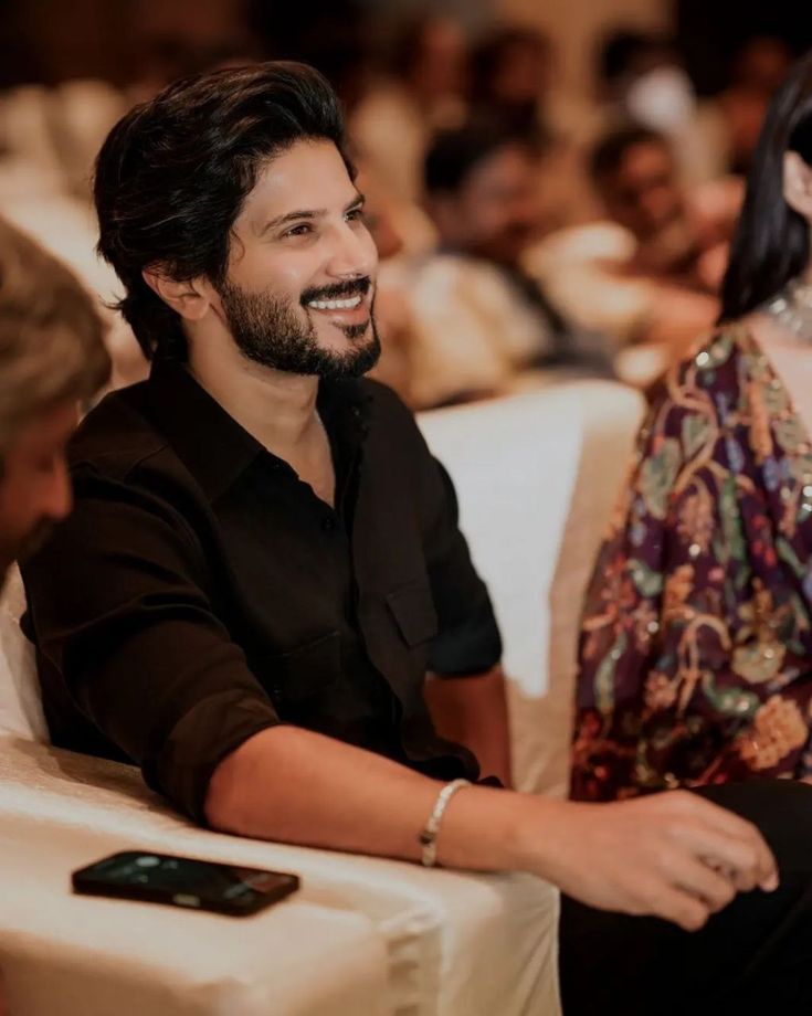 a man and woman sitting next to each other in front of a group of people