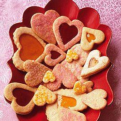 heart shaped cookies in a red bowl on a pink tablecloth with flowers and hearts