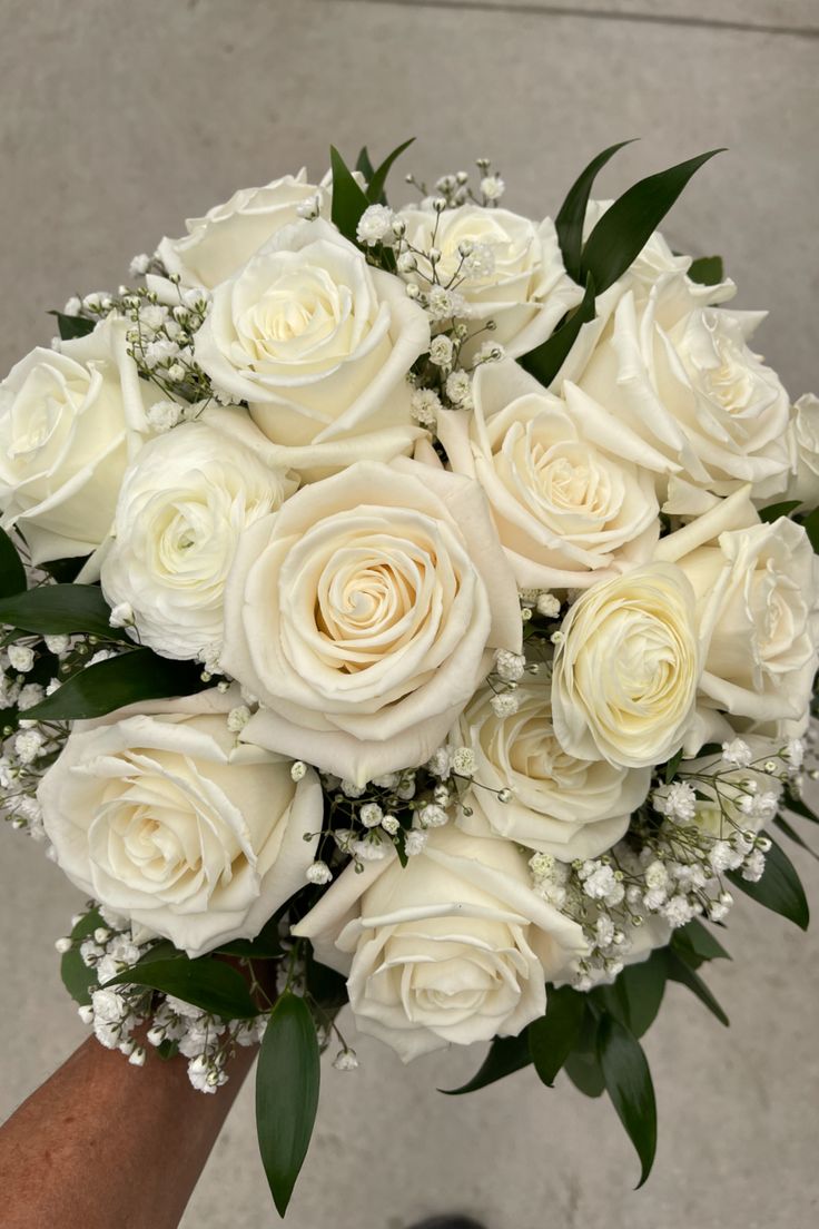 a bouquet of white roses in someone's hand