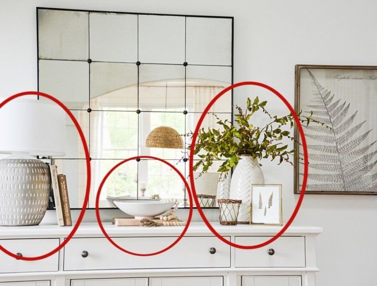 a white dresser topped with a mirror and red circles