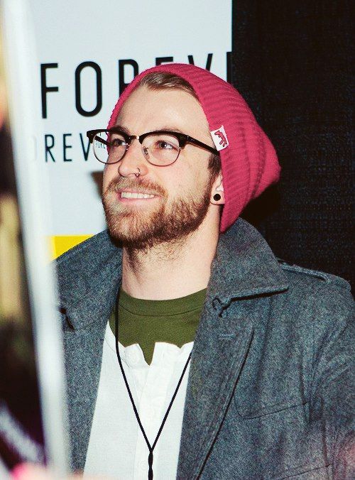 a man with glasses and a pink hat is looking at something in front of him