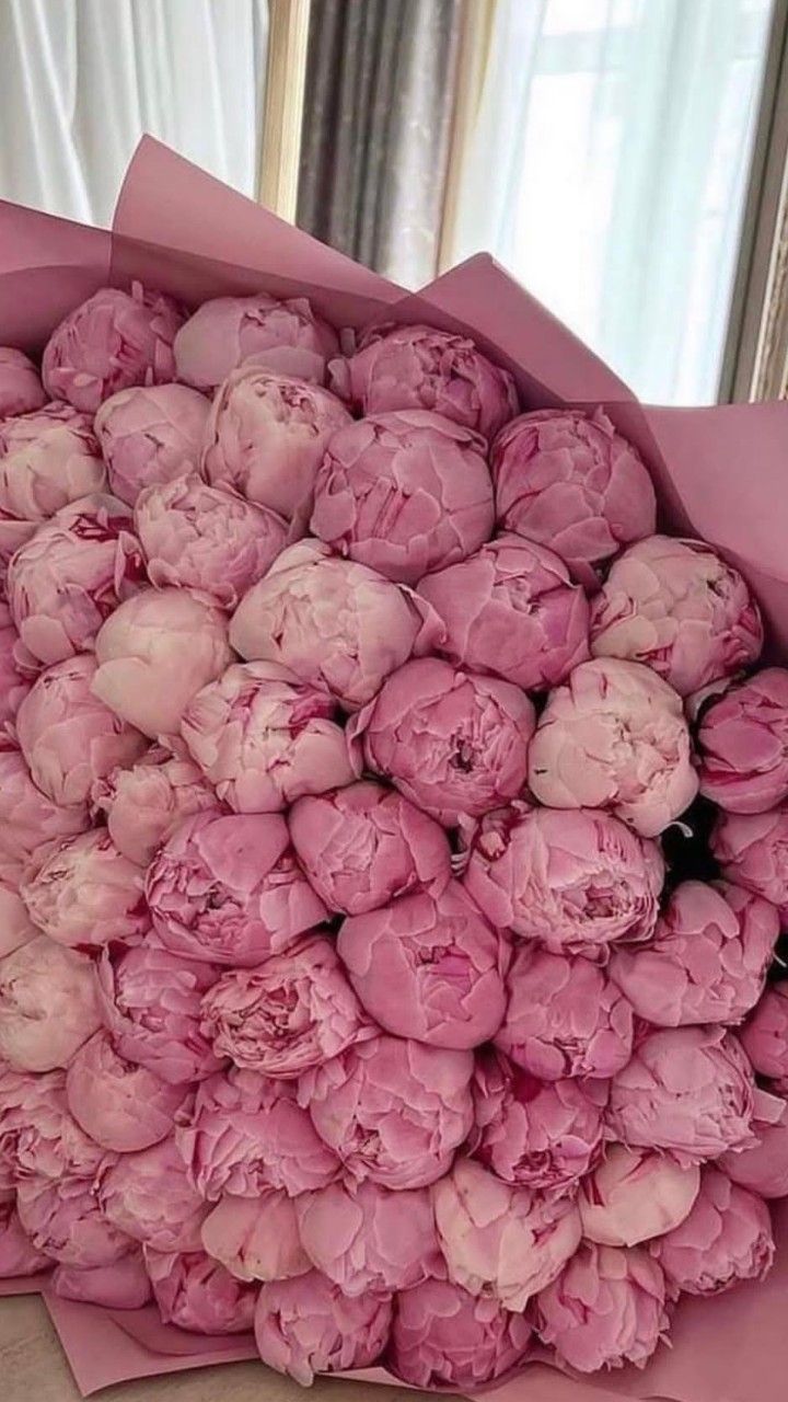 a bouquet of pink peonies sitting on top of a table