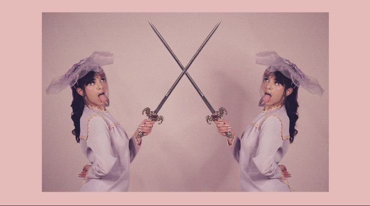 a woman holding two swords in front of her face and making a funny face with it's tongue