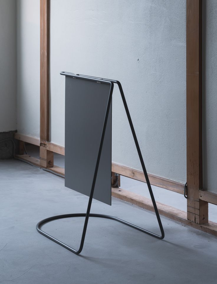 a gray sign sitting on top of a floor next to a white wall and wooden frame