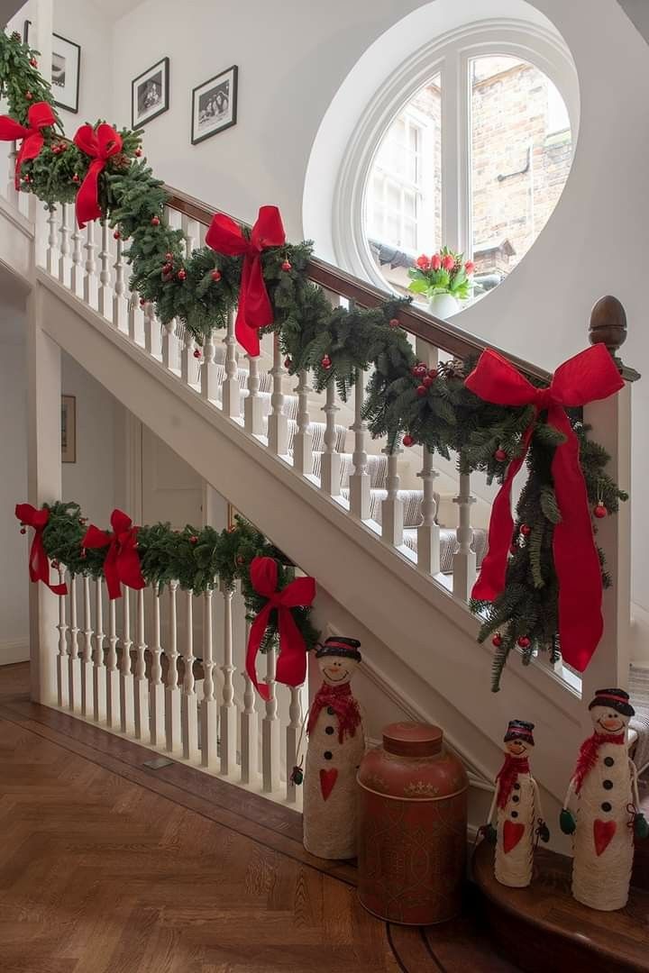 christmas decorations on the banisters and stairs are decorated with red bows, holly wreaths and snowmen