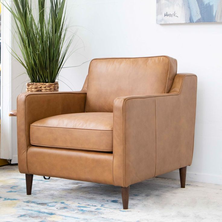 a brown leather chair sitting next to a potted plant