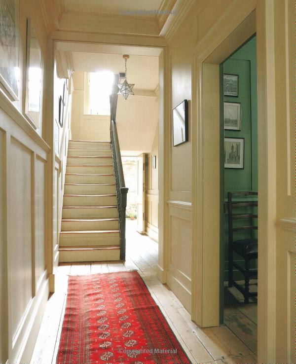 an image of a hallway with stairs and rugs on the floor in front of it