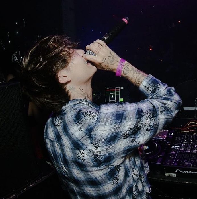 a man holding a microphone up to his face in front of a dj's equipment