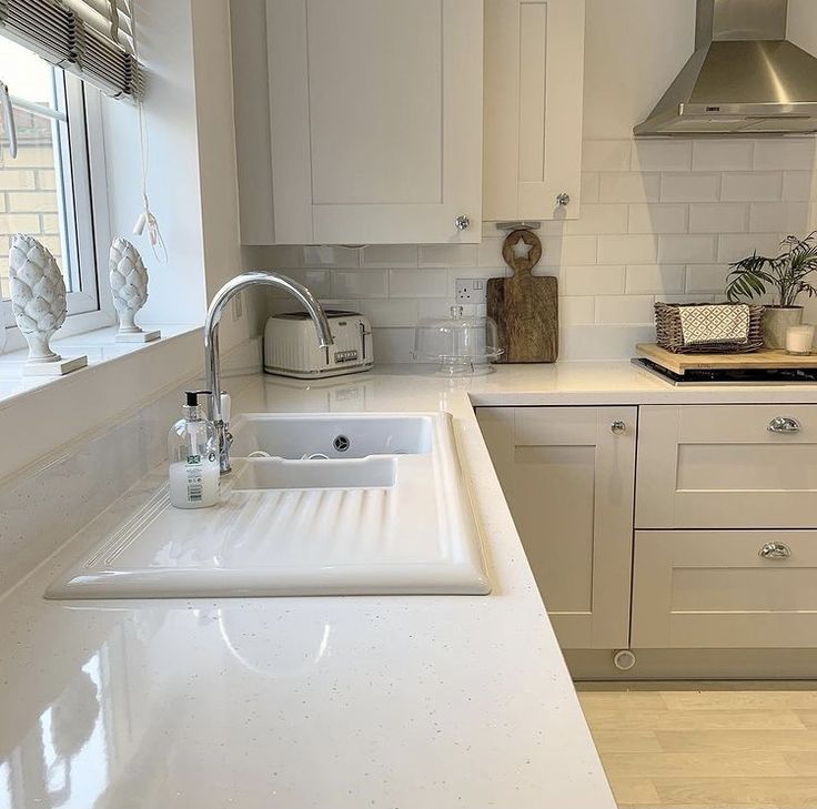 a kitchen with white cabinets and counter tops