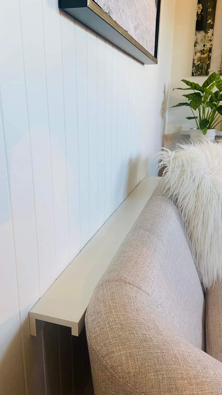 a couch with a pillow on top of it next to a potted plant in the corner