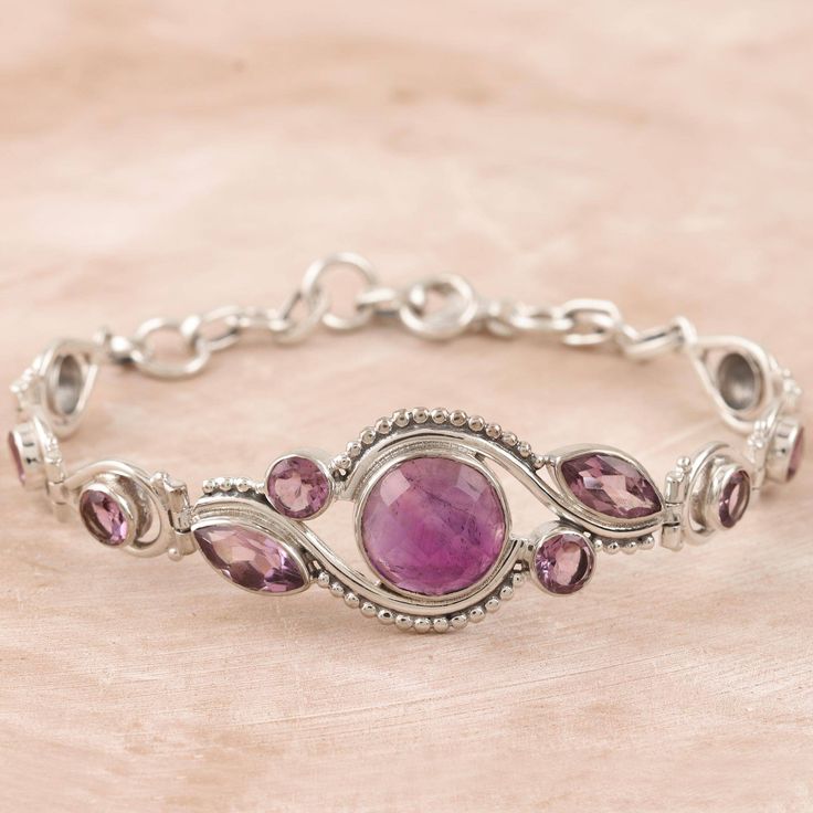 Presented by Neeru Goel, this regal bracelet features rich purple gemstones and an elegant design. Indian artisans center the bracelet with a smooth amethyst, surrounding the large gem with petite amethyst stones in bezel settings. Sterling silver accents shine next to the pretty gemstones. Formal Amethyst Gemstone Sterling Silver Bracelet, Round Amethyst Bracelets With Gemstone Accents, Formal Amethyst Bracelets With Gemstone Accents, Formal Purple Amethyst Sterling Silver Bracelet, Sterling Silver Amethyst Gemstone Bracelet For Anniversary, Purple Gemstone Sterling Silver Bracelet For Anniversary, Spiritual Sterling Silver Bracelet With Purple Gemstone, Spiritual Purple Gemstone Sterling Silver Bracelet, Elegant Purple Amethyst Sterling Silver Bracelet