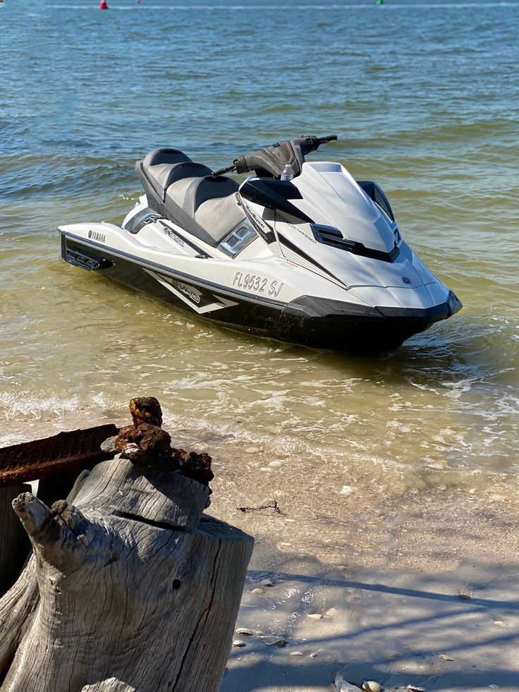 a white and black jet ski sitting on top of a beach next to the ocean