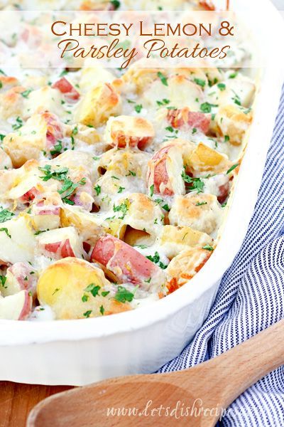 cheesy lemon and parsley potatoes in a white casserole dish with a wooden spoon