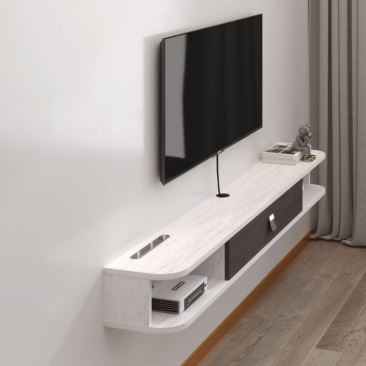 a flat screen tv mounted to the side of a white wall next to a window