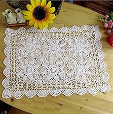 a white doily sitting on top of a wooden table next to a sunflower