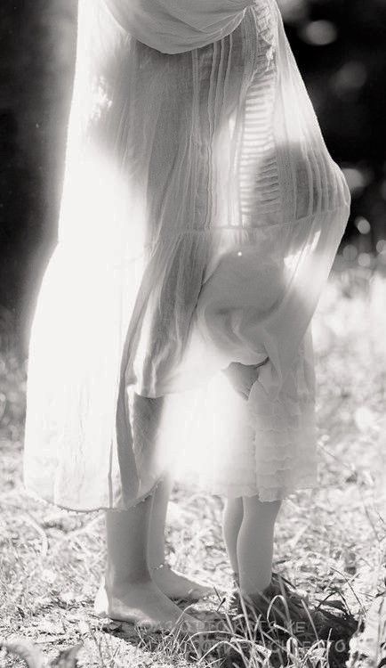 a woman bending over in the grass with her hand on her head, while she is wearing a veil