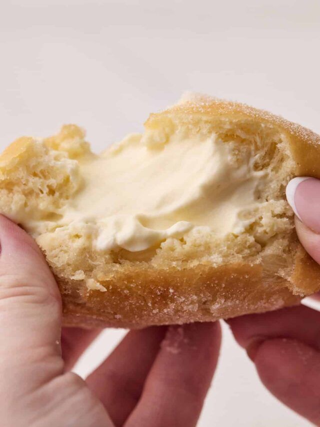 a person holding a piece of bread with cream on it