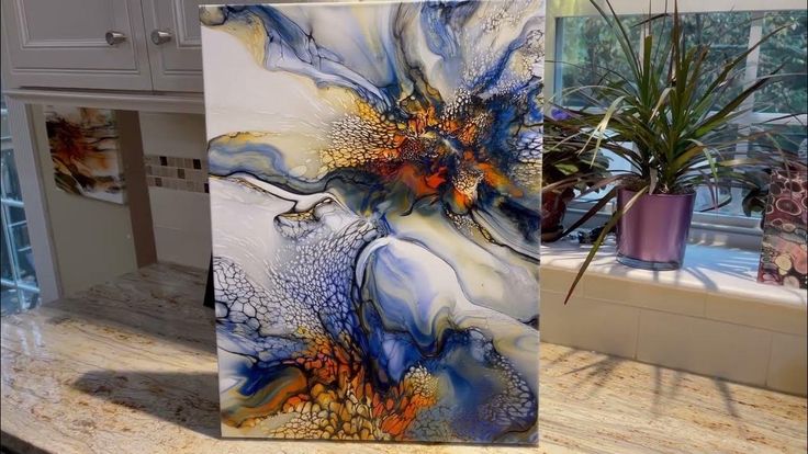 an abstract painting is displayed on a kitchen counter next to a potted houseplant