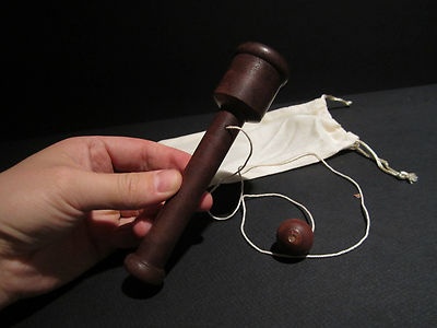 a person holding a wooden mallet on top of a black table next to a white cloth