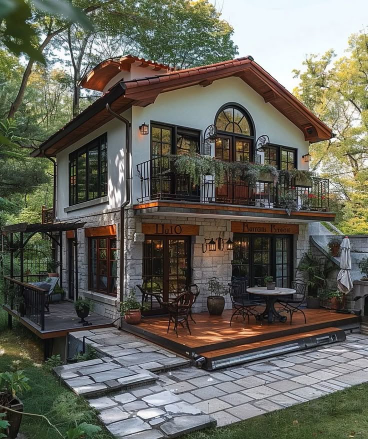 a house with a deck and patio in the front yard is surrounded by greenery