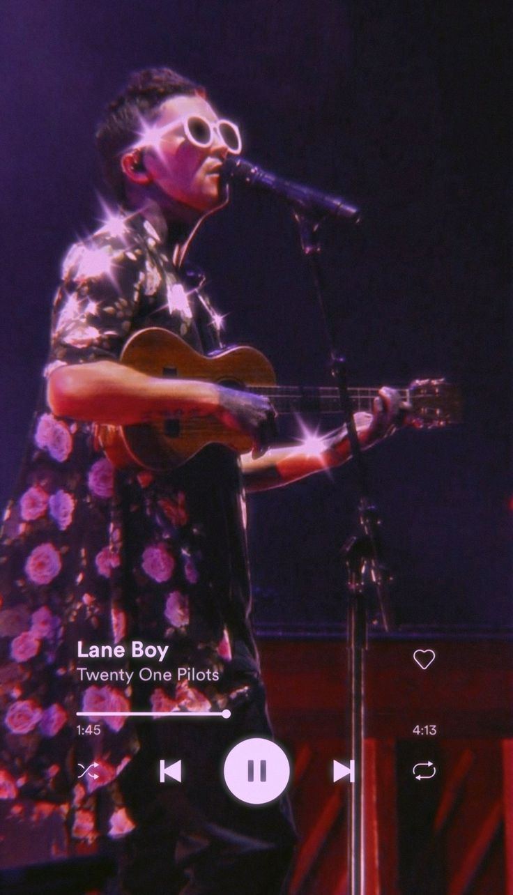 a man with sunglasses playing an acoustic guitar on the stage while holding a microphone in front of him