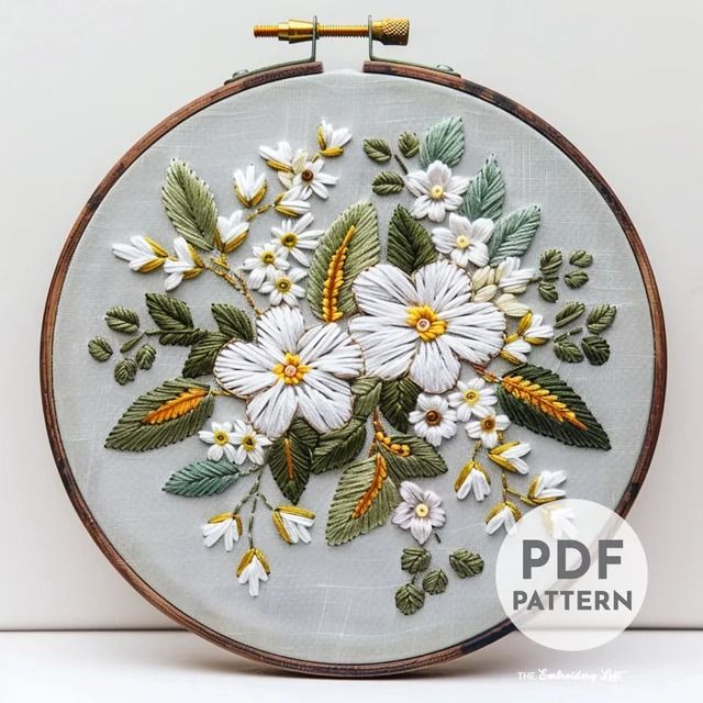 an embroidery project with white flowers and green leaves