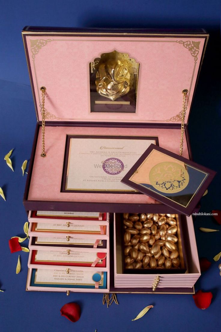 an open pink box filled with lots of different items and decorations on top of a blue surface