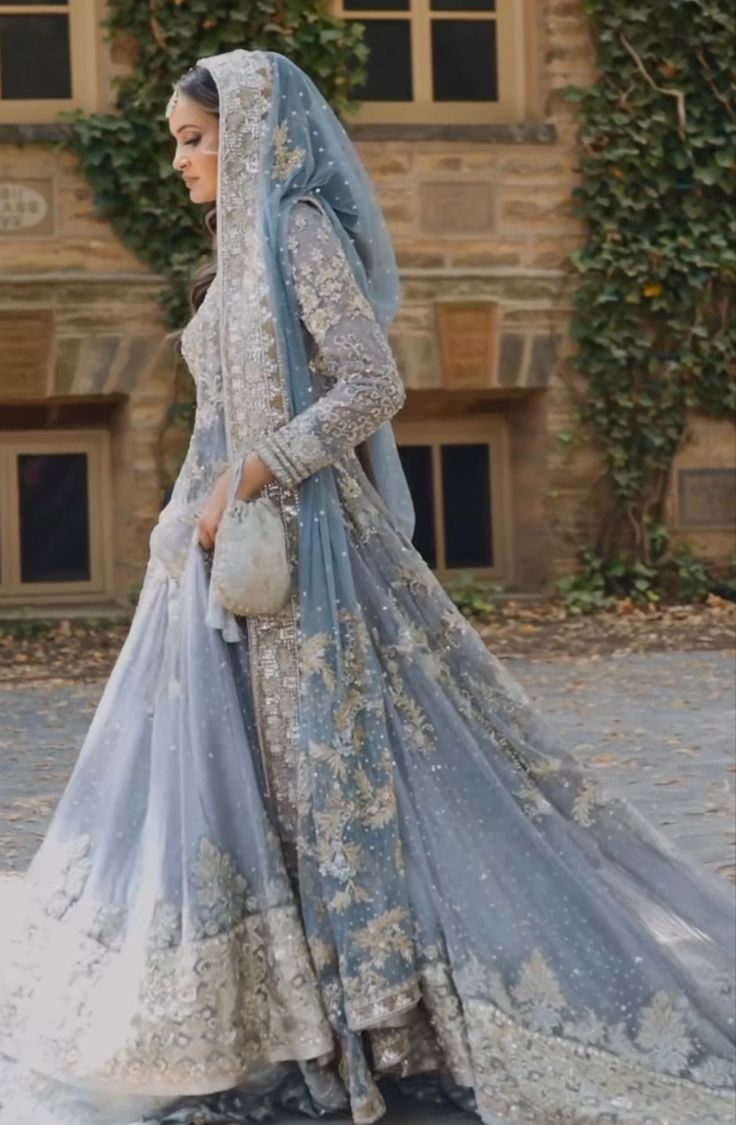 a woman in a blue and white wedding dress is walking down the street with her purse