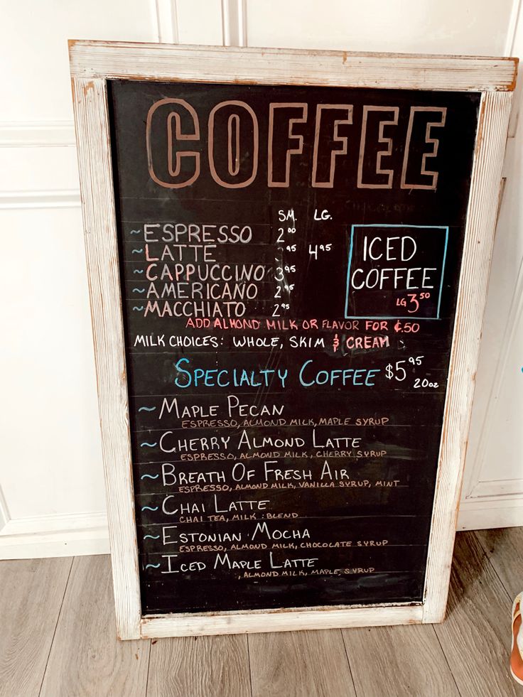 a coffee shop menu is displayed on a chalkboard in front of a door with shoes nearby