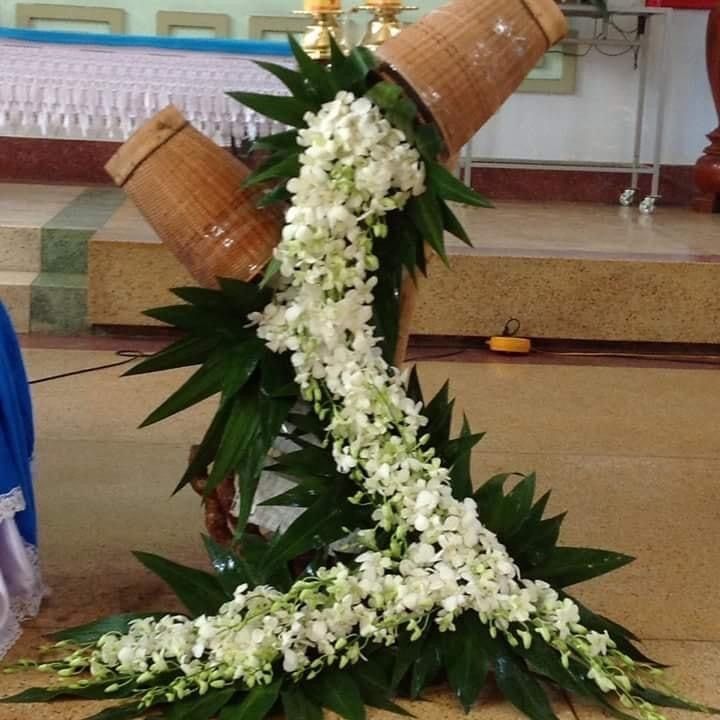 a floral arrangement is placed on the floor in front of a cross with two candles