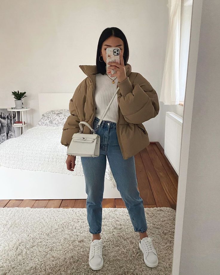 a woman taking a selfie with her phone in front of her face while standing on a carpeted floor