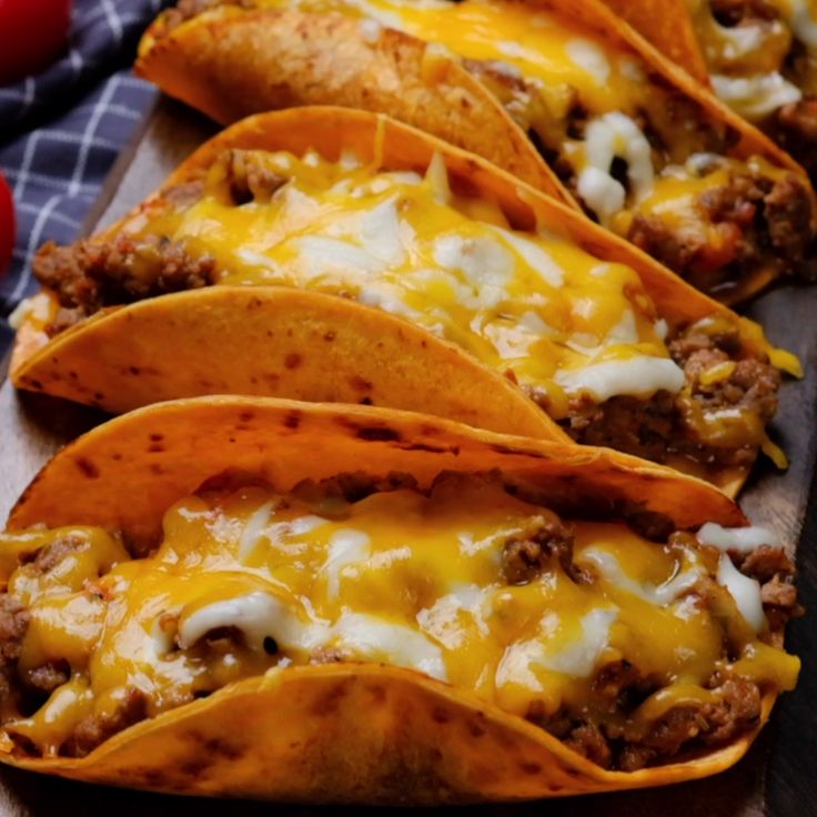 several tacos are lined up on a cutting board