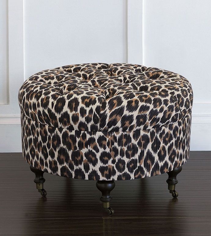 a leopard print ottoman sitting on top of a hard wood floor next to a white wall